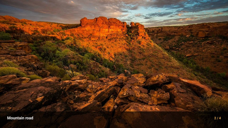 A photograph of a red sandstone gorge at sunset filling the television screen, with the caption bar along the bottom: the photo's title on the left and its position, 2 of 4, on the right.